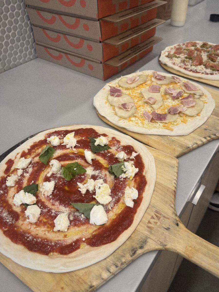 Pizzas topped and waiting on wooden peels at the Pi Co. counter